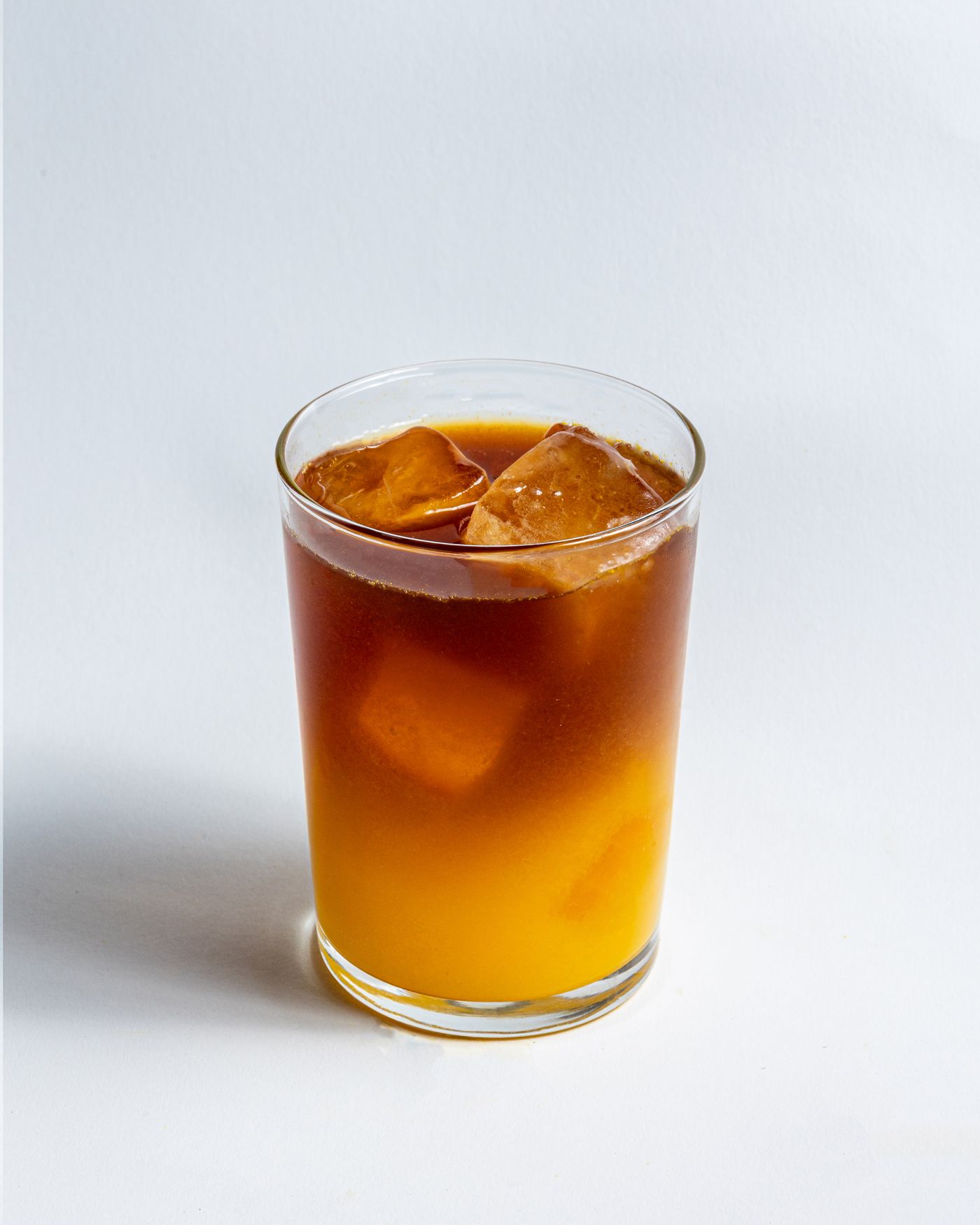Kaltes Kaffeegetränk mit Orange im Glas mit Eis